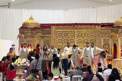 Canapé beige avec décorations dorées, tables basses et chaises blanches dans une salle ornée de panneaux lumineux bleus.