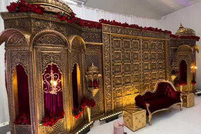 Canapé beige avec décorations dorées, tables basses et chaises blanches dans une salle ornée de panneaux lumineux bleus.
