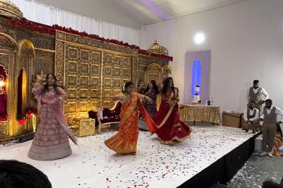 Canapé beige avec décorations dorées, tables basses et chaises blanches dans une salle ornée de panneaux lumineux bleus.