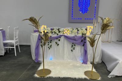 Canapé beige avec décorations dorées, tables basses et chaises blanches dans une salle ornée de panneaux lumineux bleus.