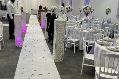 Canapé beige avec décorations dorées, tables basses et chaises blanches dans une salle ornée de panneaux lumineux bleus.