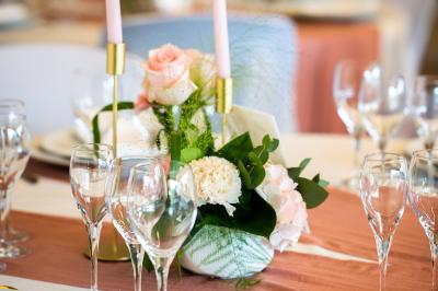 Un couple de mariés dans un jardin, la mariée tenant un bouquet de roses pastel au premier plan.