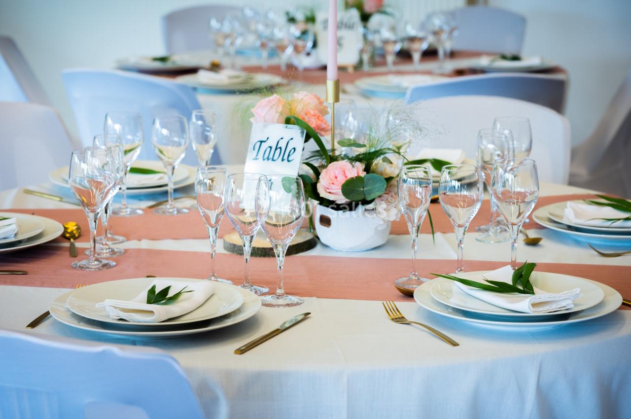 Table dressée avec une nappe blanche, vaisselle élégante, verres à pied et centre de table floral.