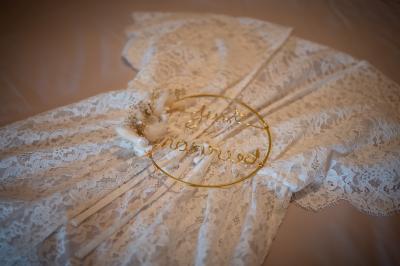 Un couple de mariés dans un jardin, la mariée tenant un bouquet de roses pastel au premier plan.