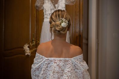 Un couple de mariés dans un jardin, la mariée tenant un bouquet de roses pastel au premier plan.