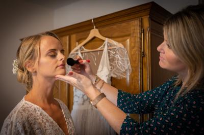 Un couple de mariés dans un jardin, la mariée tenant un bouquet de roses pastel au premier plan.