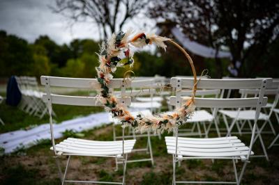 Un couple de mariés dans un jardin, la mariée tenant un bouquet de roses pastel au premier plan.