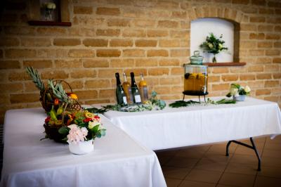 Un couple de mariés dans un jardin, la mariée tenant un bouquet de roses pastel au premier plan.
