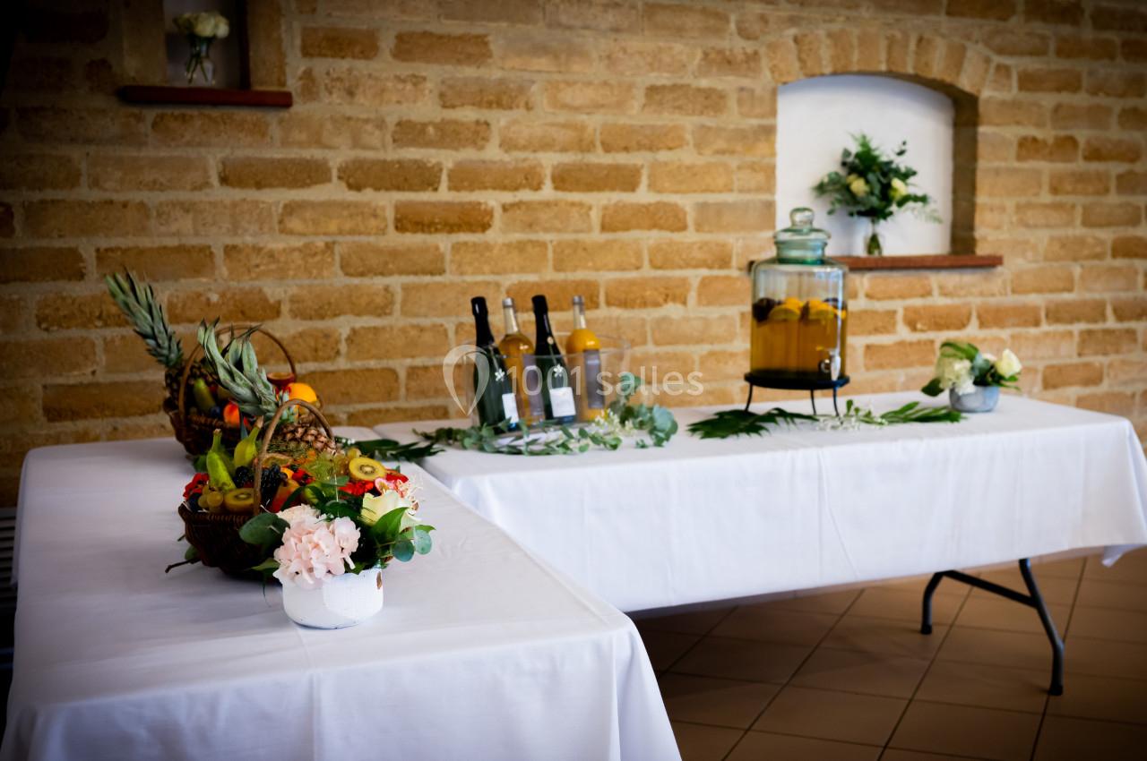 Table décorée avec des fruits, des fleurs et des boissons, dans une pièce aux murs en pierre.