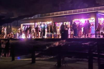 Salle de spectacle avec un public debout et assis, décorations festives et scène éclairée avec une présentation en cours.