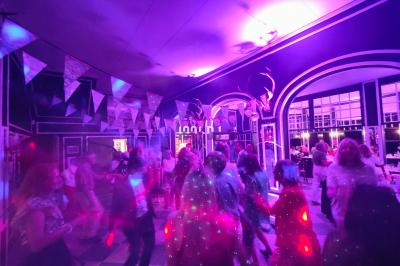 Salle de spectacle avec un public debout et assis, décorations festives et scène éclairée avec une présentation en cours.