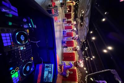 Salle de spectacle avec un public debout et assis, décorations festives et scène éclairée avec une présentation en cours.