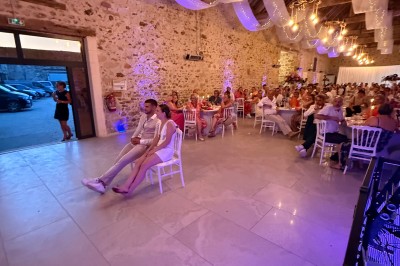 Salle de spectacle avec un public debout et assis, décorations festives et scène éclairée avec une présentation en cours.