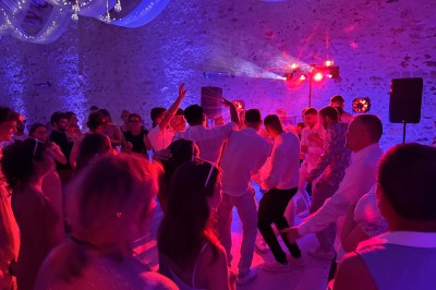 Salle de spectacle avec un public debout et assis, décorations festives et scène éclairée avec une présentation en cours.