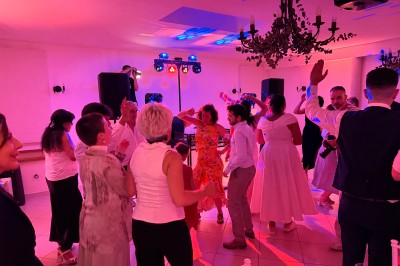 Salle de spectacle avec un public debout et assis, décorations festives et scène éclairée avec une présentation en cours.