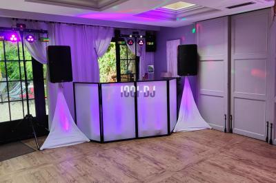 Poste de DJ éclairé en violet avec des haut-parleurs et des lumières dans une salle au décor classique.