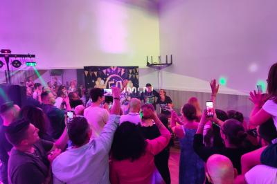 Poste de DJ éclairé en violet avec des haut-parleurs et des lumières dans une salle au décor classique.