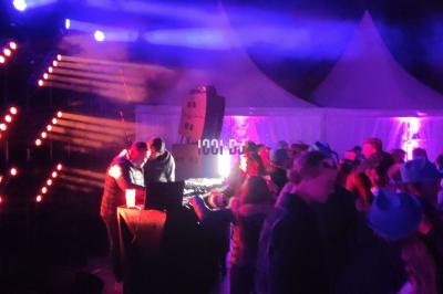 Poste de DJ éclairé en violet avec des haut-parleurs et des lumières dans une salle au décor classique.