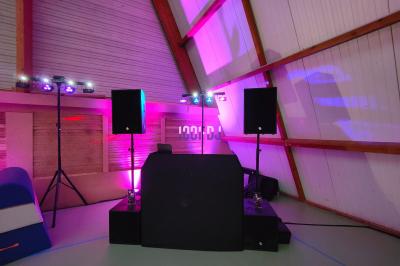 Poste de DJ éclairé en violet avec des haut-parleurs et des lumières dans une salle au décor classique.