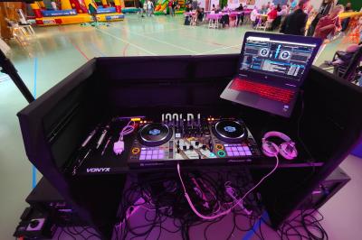 Poste de DJ éclairé en violet avec des haut-parleurs et des lumières dans une salle au décor classique.