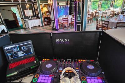 Poste de DJ éclairé en violet avec des haut-parleurs et des lumières dans une salle au décor classique.