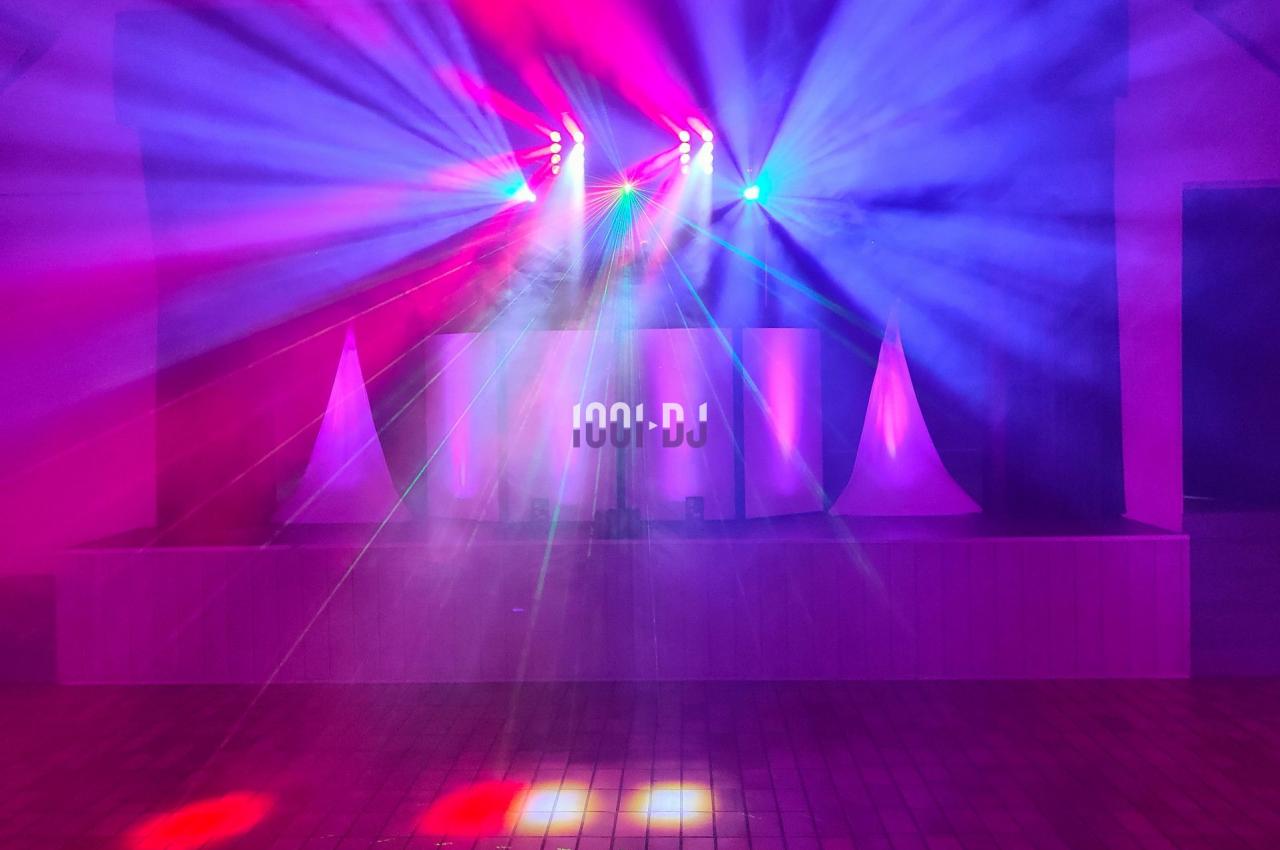 Jeu de lumières colorées projetées dans une salle sombre avec un sol carrelé et un espace de scène.