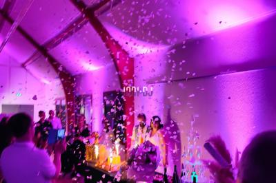 Poste de DJ éclairé en violet avec des haut-parleurs et des lumières dans une salle au décor classique.