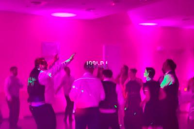 Poste de DJ éclairé en violet avec des haut-parleurs et des lumières dans une salle au décor classique.