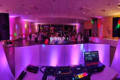 Poste de DJ éclairé en violet avec des haut-parleurs et des lumières dans une salle au décor classique.