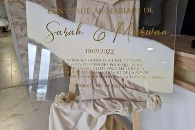 Salle de réception décorée avec des fleurs blanches, un canapé élégant sur une estrade et des tables dressées.