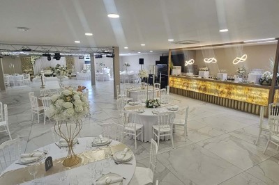 Salle de réception décorée avec des fleurs blanches, un canapé élégant sur une estrade et des tables dressées.