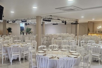 Salle de réception décorée avec des fleurs blanches, un canapé élégant sur une estrade et des tables dressées.