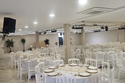 Salle de réception décorée avec des fleurs blanches, un canapé élégant sur une estrade et des tables dressées.