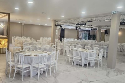 Salle de réception décorée avec des fleurs blanches, un canapé élégant sur une estrade et des tables dressées.