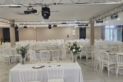 Salle de réception décorée avec des fleurs blanches, un canapé élégant sur une estrade et des tables dressées.