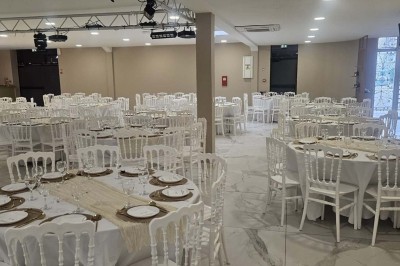 Salle de réception décorée avec des fleurs blanches, un canapé élégant sur une estrade et des tables dressées.