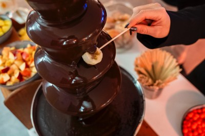 Une personne tranche un filet de saumon sur une planche en bois, avec des toasts préparés en premier plan.