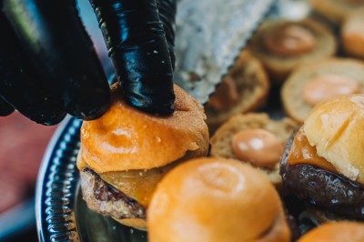 Une personne tranche un filet de saumon sur une planche en bois, avec des toasts préparés en premier plan.