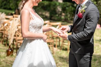Un marié aide sa partenaire en robe de mariée à sortir d'une voiture ancienne décorée pour un mariage.