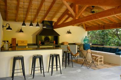 Salle en pierre avec de grandes tables dressées, éclairée par des lustres faits de bouteilles en verre vert.