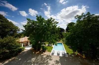 Salle en pierre avec de grandes tables dressées, éclairée par des lustres faits de bouteilles en verre vert.