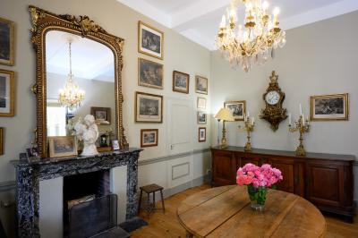 Salle en pierre avec de grandes tables dressées, éclairée par des lustres faits de bouteilles en verre vert.
