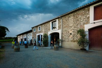 Salle en pierre avec de grandes tables dressées, éclairée par des lustres faits de bouteilles en verre vert.