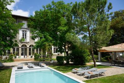 Salle en pierre avec de grandes tables dressées, éclairée par des lustres faits de bouteilles en verre vert.