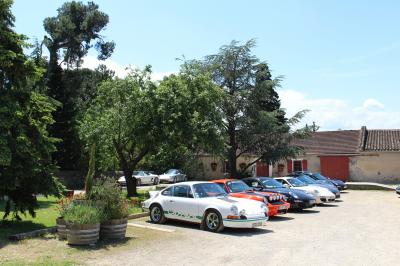 Salle en pierre avec de grandes tables dressées, éclairée par des lustres faits de bouteilles en verre vert.