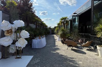 Salle de réception élégante avec tables rondes dressées, chaises transparentes et lustres suspendus.