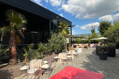 Salle de réception élégante avec tables rondes dressées, chaises transparentes et lustres suspendus.
