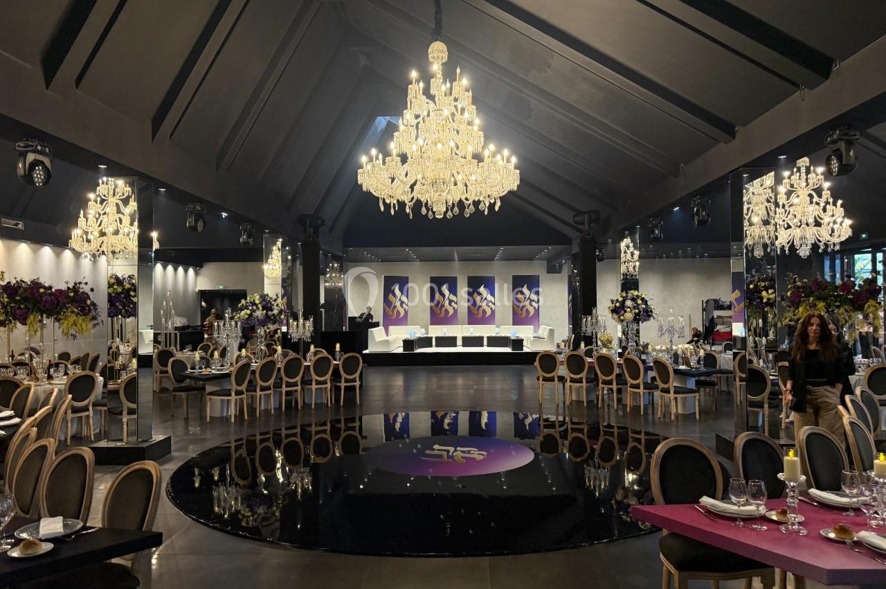 Salle de réception élégante avec lustres en cristal, tables dressées et décorations florales colorées.