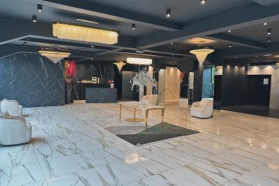 Salle de réception élégante avec tables rondes dressées, chaises transparentes et lustres suspendus.