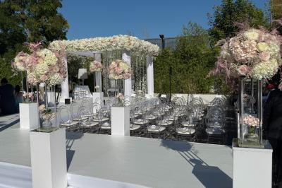 Salle de réception élégante avec tables rondes dressées, chaises transparentes et lustres suspendus.